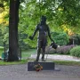 Pushkin statue in a park beside a body of water, with trees and paddle boats in the background.