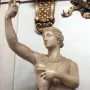 Marble statue of a wounded Amazon standing with one arm raised and a short tunic.