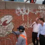 Workers clean graffiti from the Monument to General Carlos M. de Alvear while two men observe nearby.