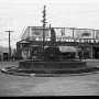 Chief Seattle statue with a raised arm on an ornate pedestal in a circular street island.