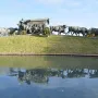 The Monument to the Cart, a bronze sculpture of a covered cart pulled by oxen with a rider on horseback nearby, reflected in a pond.