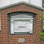 Titanic Musicians\' Memorial plaque set in a red brick archway with carved inscriptions and a relief of a musician playing an instrument.