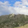 Our Lady of the Rockies statue standing on a rocky, tree-covered mountain summit