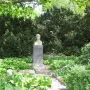 Bust of Stanisław Wyspiański on a tall stone pedestal in a garden