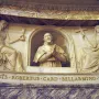 Marble relief monument of Cardinal Roberto Bellarmine in an arched niche, flanked by seated female figures holding a chalice, book, and crucifix.
