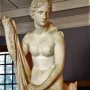 Mazarin Venus, a carved stone statue of a standing female figure holding draped cloth, with a dolphin-like creature at her feet.