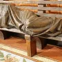 Bronze Homeless Jesus sculpture of a covered figure lying on a slatted bench, with bare feet visible at one end.