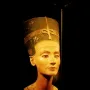 Bust of Nefertiti with a tall decorated crown, broad collar, and one missing eye socket