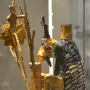 Ram in a Thicket figurine with a golden head, dark horns, and a scale-like body beside a leafy tree.