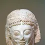 Marble head of the Rampin Rider with elaborate curls, a laurel wreath, and a damaged nose.
