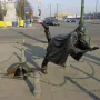 Vaartkapoen bronze statue showing a helmeted figure falling backward as another emerges from a manhole to grab their leg.