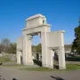 Confederate Memorial Gateway with a large central arch and two smaller side arches beside a cemetery road.