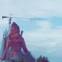 Statue of Belief under construction, draped in scaffolding and protective netting with a crane beside it.