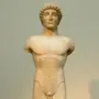 Apollo Strangford marble kouros statue with missing arms and lower legs, shown frontally on a dark base.