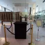 The Warka Mask displayed in a glass case on a dark pedestal in a museum hall.