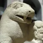 Close-up of the Bear of Porcuna stone sculpture, showing a carved animal head beside a smaller human head.