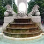 Fountain of Hercules with two carved lions on spheres spraying water into a stone basin.