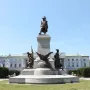 Tadeusz Kościuszko Monument with a bronze figure on a pedestal, flanked by additional sculptures including an eagle in a grassy park.