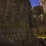 Yazılıkaya rock reliefs carved along a large stone wall in a narrow passage with sky visible above.
