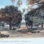 The Defenders of Fort Moultrie monument in a tree-filled park, with a tiered stone base and a figure holding a flag on top.