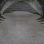 Infinite Wave memorial with arched metal bars forming a tunnel-like walkway beside a curved stone wall.