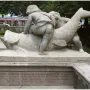 Rhine Water Fountain sculpture with two youthful figures and a large fish-like creature, with red inscription on the base.