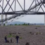 Visitors climb the stairway of the Tetrahedron steel lattice structure, with children exploring the rocky base below.