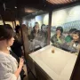 Meat-Shaped Stone displayed on a pedestal inside a glass case with museum visitors nearby.