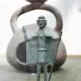 Nuragic bronze statuette of a tribal chief with a raised arm and staff, mounted on a wooden base.