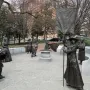 Virginia Women’s Monument sculpture with a central figure holding a tall Votes for Women banner, with additional statues on a stone patio behind it.