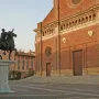 Regisole equestrian statue on a pedestal in a paved square with the cathedral of Pavia behind it.