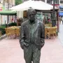 Woody Allen Memorial sculpture of a man in spectacles, jacket, and loose trousers standing with hands in pockets.