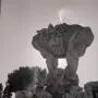 The Fountain of the Tritons with two muscular figures supporting a shell-shaped basin as water sprays upward and cascades down.