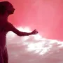 La madre del emigrante statue of a woman with an arm extended, silhouetted against a dramatic pink and white sky.