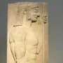 Grave stele with a relief of a youthful male figure in profile holding a staff.