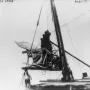 Golden Boy statue being hoisted by cables, with wooden bracing and workers below guiding the lift.