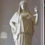 Giustiniani Hestia, a white marble statue of a standing woman in a long pleated robe with a mantle over her head and shoulders.
