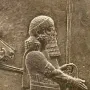 Detail of the Lion Hunt of Ashurbanipal relief showing a bearded figure in profile with a spear and ornate robe.