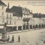 Statue of the Volunteer of 1792 on a pedestal beside a cobblestone street with arched arcades and pedestrians.