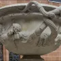 Side view of the Warwick Vase, showing its ornate carved heads and intertwined vine-like handles.