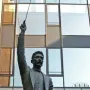 A bronze statue of A Lluís Millet in a formal suit and bow tie, with one arm raised and pointing upward.