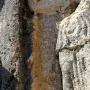 Ancient inscription carved into a weathered rock face beside the Athena relief.