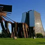 Monument to the Azoreans standing on a green lawn with a modern building in the background.
