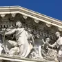 White marble pediment sculpture from Apotheosis of Democracy showing a crowned female figure with a torch beside smaller classical figures.