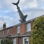 The Headington Shark sculpture protruding headfirst from the roof of a red brick house in Oxford.