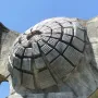 Textured dome detail of the Monument to the Revolution of the People of Moslavina against a blue sky.