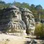 The Devil\'s Heads sandstone carvings, with two massive carved faces in a forest setting.