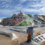 Salvation Mountain with colorful painted stripes, large hearts, religious messages, and a white cross on top.