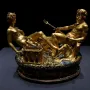 Cellini Salt Cellar with a reclining female figure and a seated male figure holding a trident on a detailed golden base.