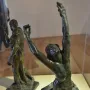 The Prodigal Son bronze statue of a kneeling nude man with arms raised and head thrown back, with another robed figure behind him.
